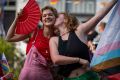 Young girl holding a flag and kissing a girl on her cheek with smiles during the canal pride 2024